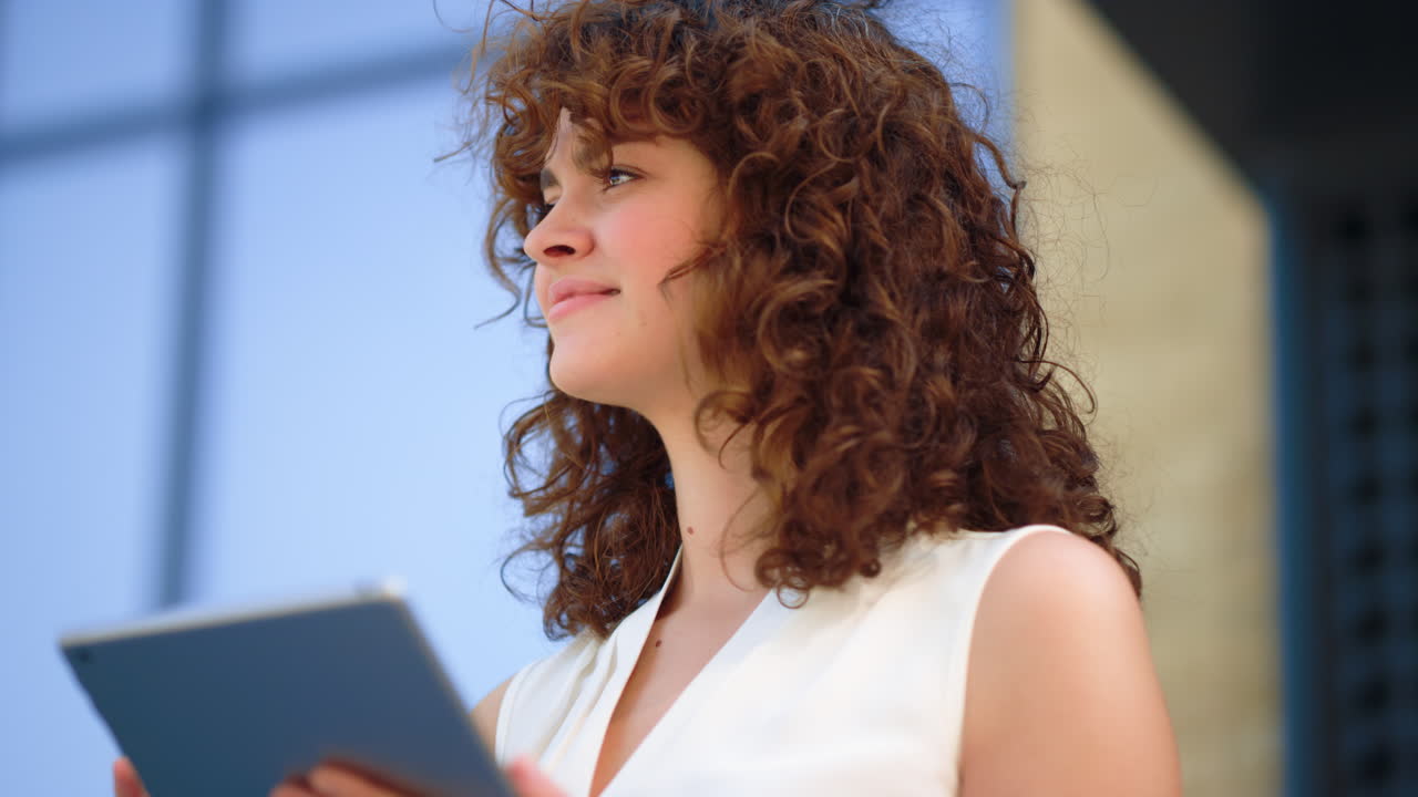Pretty woman using tablet outside. Cute girl greetings someone outdoors.