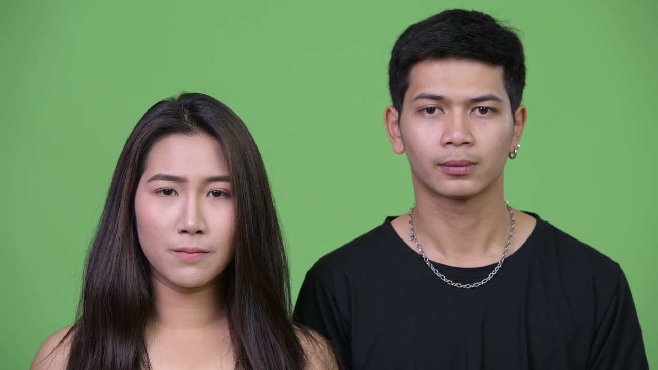 Young upset Asian woman with young Asian man covering face