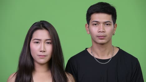 young upset asian woman with young asian man covering face