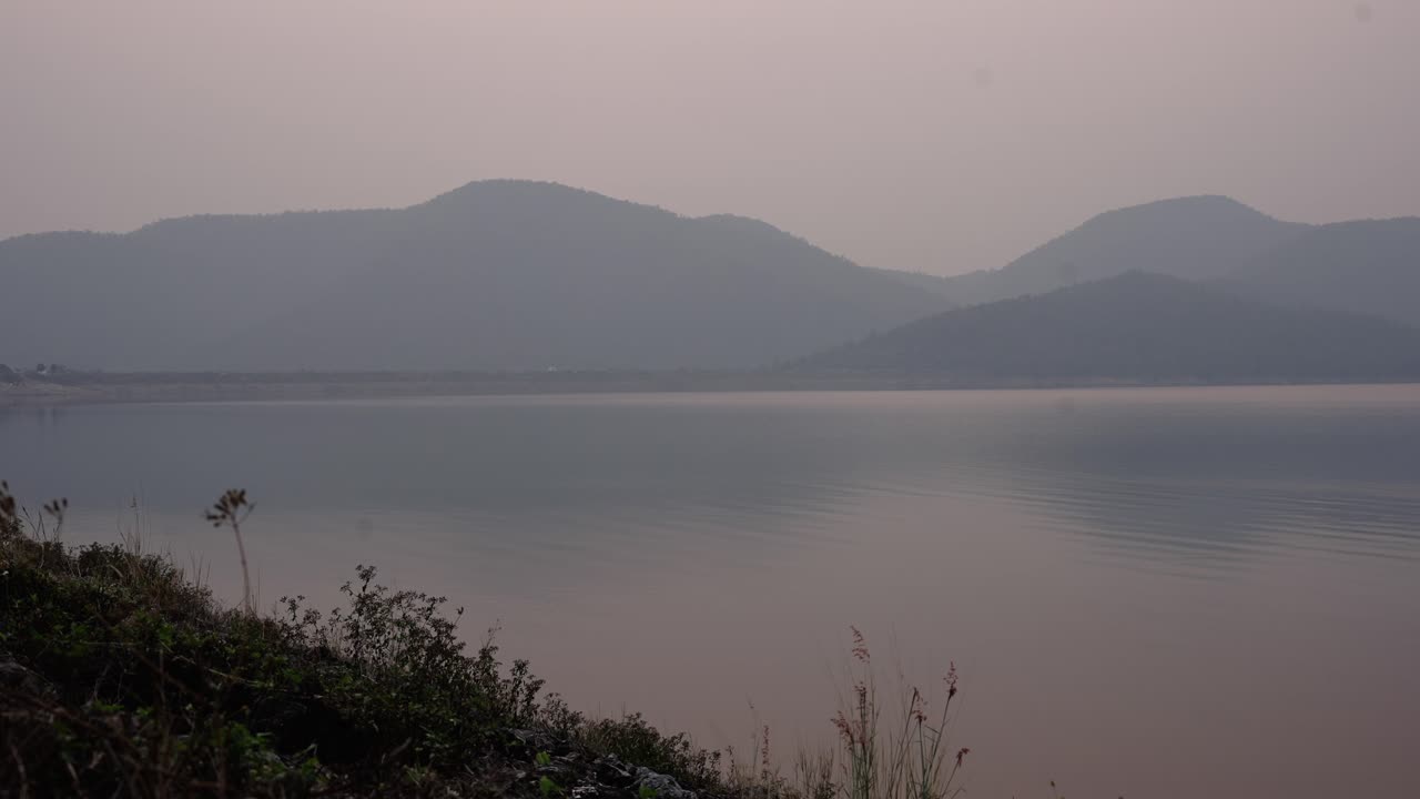 Hazy Sunset over a Tranquil Lake and Mountains