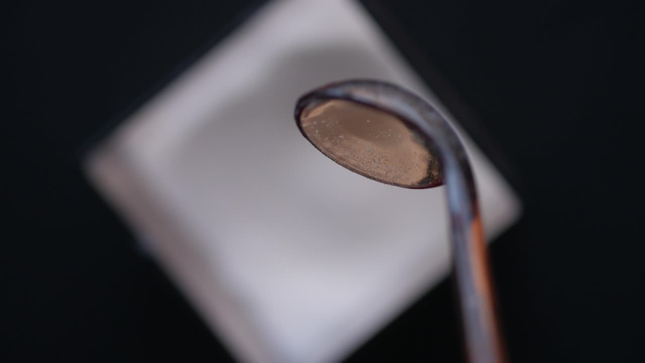 una cuchara de azúcar en una superficie blanca.