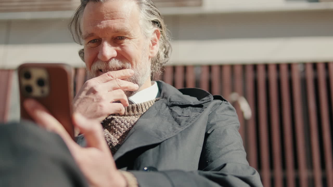 웃는 남자가 야외에서 전화를 사용합니다.