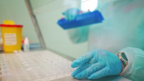 preparation for blood test. doctor hand taking a blood sample tube from a rack with machines of analysis in the lab background