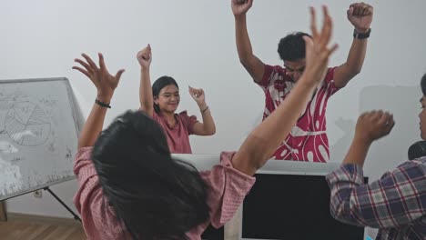happy asian college students giving high five and cheering for their success in computer class
