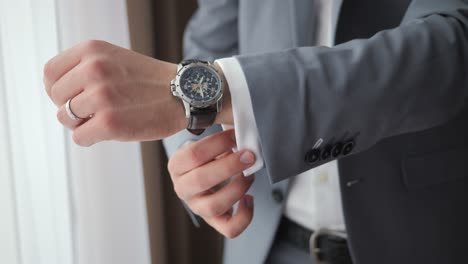 close-up shot of man adjusting his watch and suit cufflinks - gentleman wearing a watch