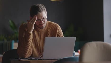 thoughtful serious man student writer sit at home office desk with laptop thinking of inspiration search problem solution ideas lost in thoughts concept dreaming looking away