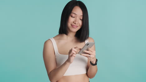asian woman texting on smartphone and smiling.