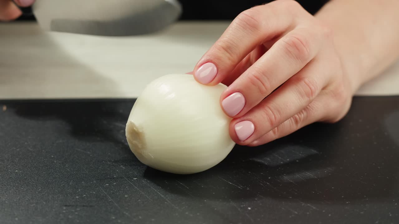 흰 양파를 도마 위에서 썰고 있는 여성의 클로즈업 매크로 사진