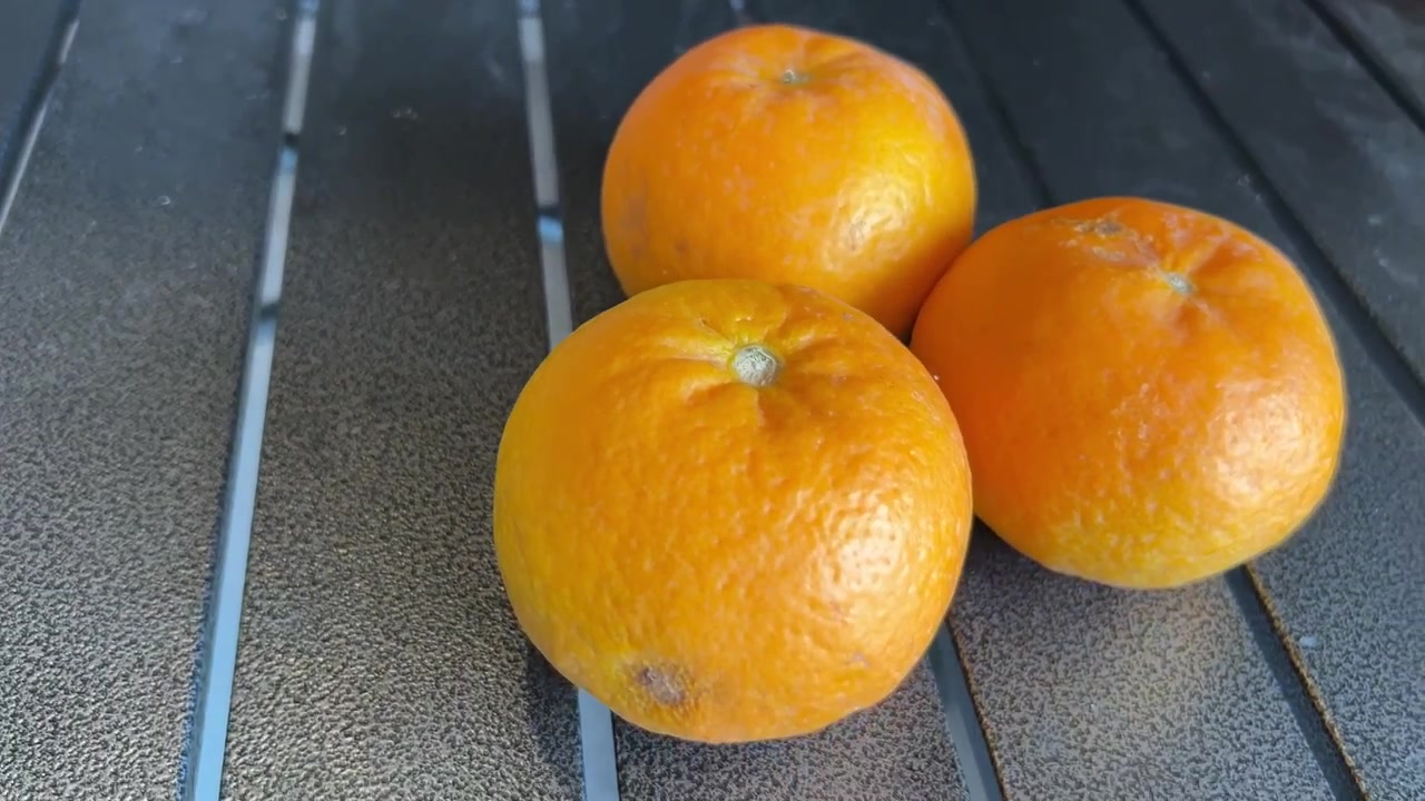Primer plano con zoom de tres naranjas frescas sobre una mesa oscura