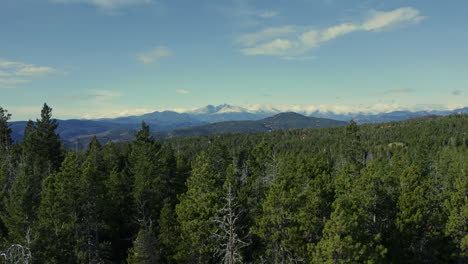 Luftaufnahmen,-Die-Aus-Dem-Wald-Aufsteigen-Und-In-Der-Ferne-Große-Schneebedeckte-Berge-Sichtbar-Machen,-4k