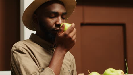 male customer enjoying fresh smell of green apples in crates