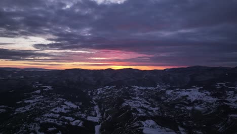 Captivating aerial view of a sunset over snow-covered mountains, showcasing vibrant skies and peaceful winter landscapes