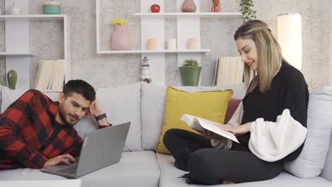 una joven pareja feliz sentada en el sofá en casa, teniendo un tiempo agradable e íntimo.