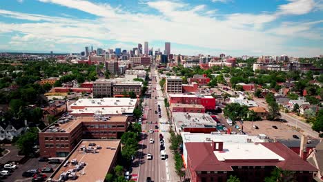 Downtown-Denver-South-Broadway-street-aerial-drone-view-City-landscape-businesses-restaurants-traffic-cars-pedestrian-traffic-bike-crossing-road-summer-sunny-afternoon-clouds-skyscraper-upward-motion