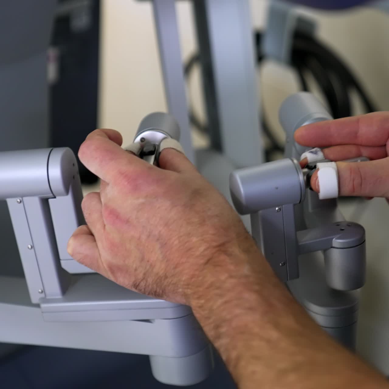 Surgeon's hands take the motion controllers of robotic equipment. Doctor puts the special fasteners on his finger. Starting the surgery with robotic system