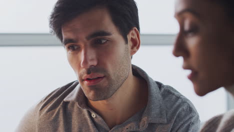 Pull-Focus-Close-Up-Of-Businesswoman-Working-On-Laptop-At-Desk-With-Male-Colleague