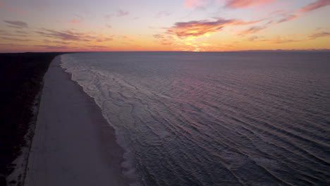 Vista-Aérea-Del-Mar-Báltico-Durante-La-Puesta-De-Sol-Dorada-Y-El-Cielo-Púrpura-En-Krynica-Morska,-Polonia