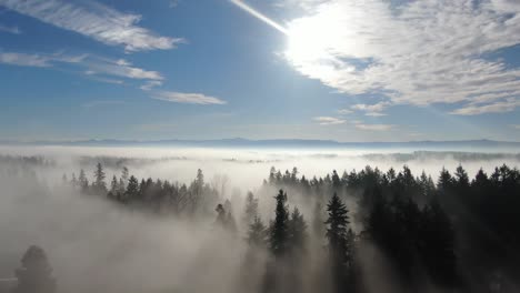 Drohnenflug-Am-Frühen-Morgen-über-Neblige-Felder-Mit-Blauem-Himmel-Und-Bergen-Im-Hintergrund