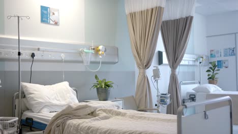 habitación de hospital con camas, plantas y cortinas beige, cámara lenta