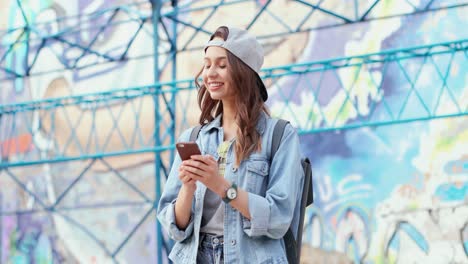 Chica-Caucásica-Con-Gorra-Enviando-Mensajes-De-Texto-En-El-Teléfono-Inteligente-En-La-Calle