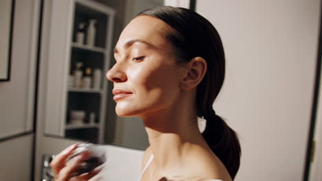woman applying skincare product to her face and neck