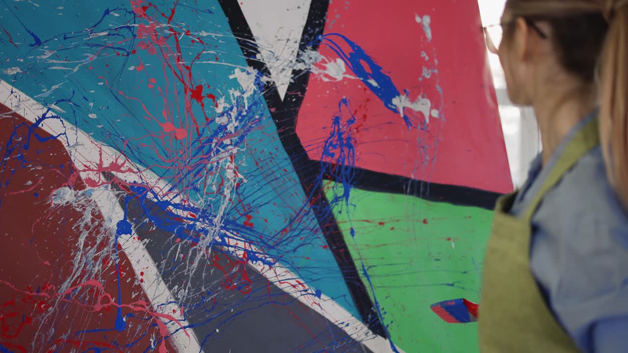 la mujer usa pincel ancho y pinturas de color salpicando el gesto en el lienzo, primer plano