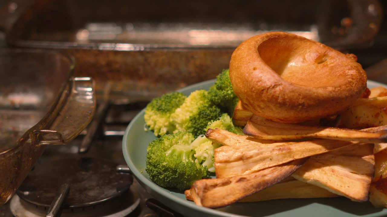 Pan From Empty Cooking Glass Trays to Reveal Traditional British Roast Dinner Plate with Vegetables including Parsnips, Broccoli, Roast Potatoes, Carrots and Yorkshire Pudding on Top 4K