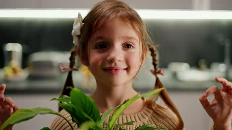 Portrait-Close-up-of-a-happy-little-calm-brown-haired-girl-with-a-braided-hairstyle-sits-in-the-lotus-position-and-practices-Zen-and-meditation-with-a-houseplant-in-a-modern-kitchen-in-the-evening