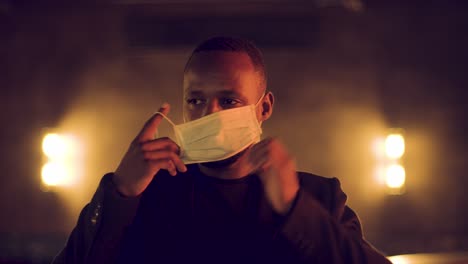 male smiling and winking at camera and putting on a medical mask