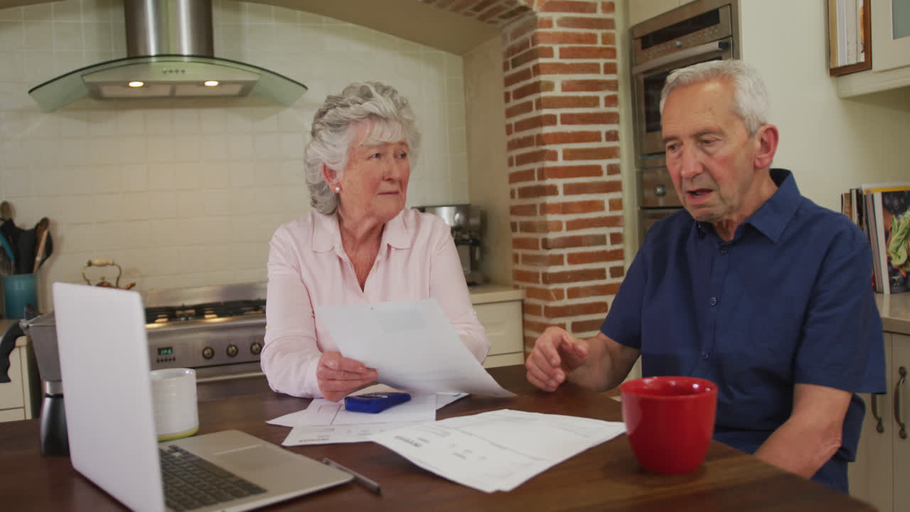 una pareja caucásica está sentada en la cocina comprobando el papeleo.