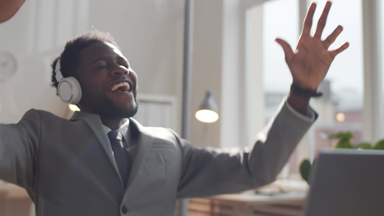 feliz hombre de negocios afroamericano con auriculares escuchando música en el trabajo