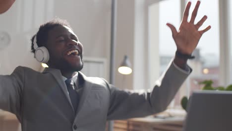 happy afro-american businessman in headphones listening to music at work