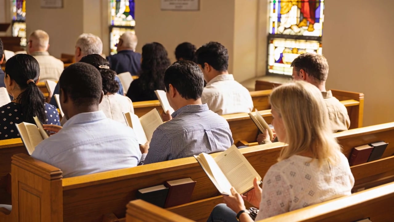 Reading seated congregants during service in church pews, holding hymnals in stained-glass light