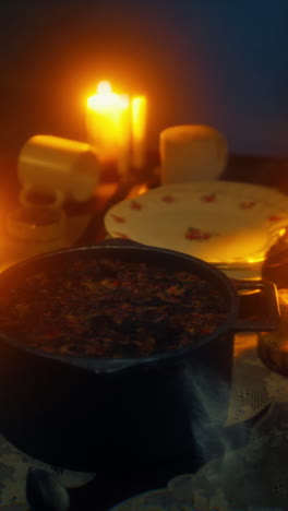 steaming pot of food on a rustic table with candlelight