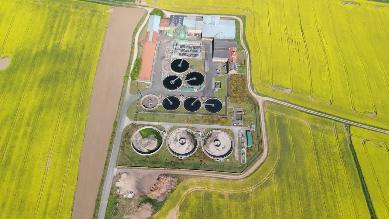 Aerial drone view of a wastewater treatment plant in a bright yellow rapeseed field on a sunny summer day in North Yorkshire, UK