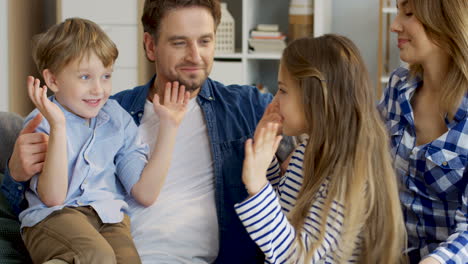 niños pequeños alegres, niños y niñas, sentados en las rodillas de sus padres y jugando un juego de manos