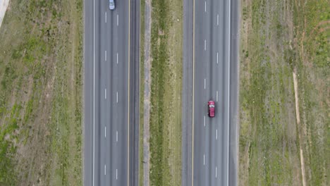 cars and trucks driving on a divided highway while the camera looks straight down