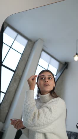 woman applying makeup in front of a mirror