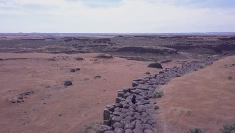 Aerial-view:-Hiker-walks-atop-basalt-rock-columns-in-Scablands-of-WA