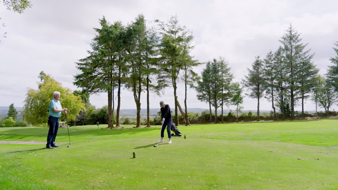 Golf players playing golf and knocking golf ball out on golf course on cloudy day
