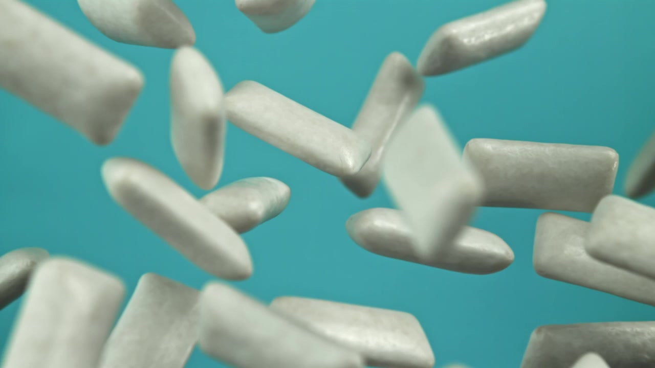 Pedaços de chiclete branco caindo em câmera lenta sobre um fundo azul