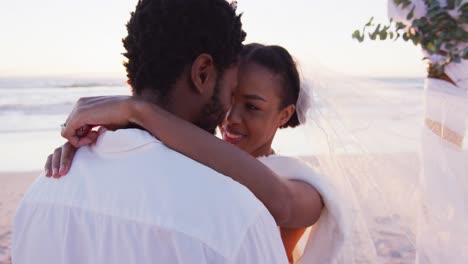 Afroamerikanisches-Verliebtes-Paar-Heiratet,-Lächelt-Und-Schaut-Sich-Bei-Sonnenuntergang-Am-Strand-Andere-An