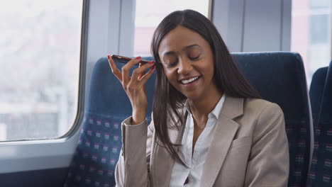 businesswoman sitting in train commuting to work using mobile phone