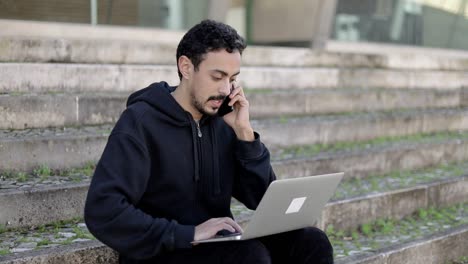 hombre usando computadora portátil y hablando por teléfono inteligente