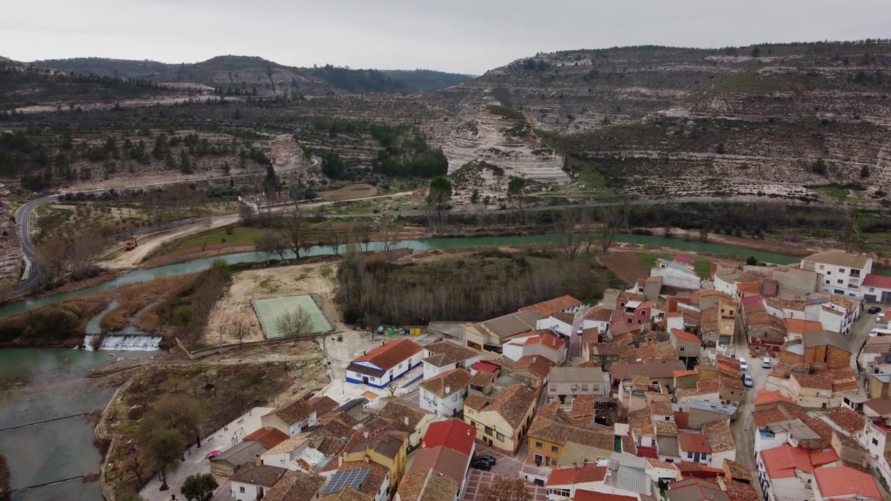 Ascenso escénico de dron aéreo 4K e inclinación de cámara hacia abajo sobre el pueblo de La Ricueja, España, en el cañón del río Júcar con sus distintivas terrazas agrícolas.