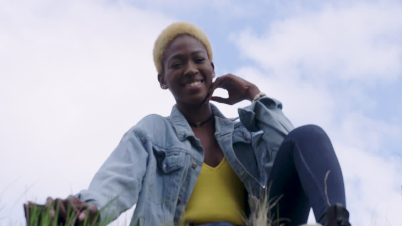 mirando a una mujer joven y atractiva sentada en la hierba y sonriendo