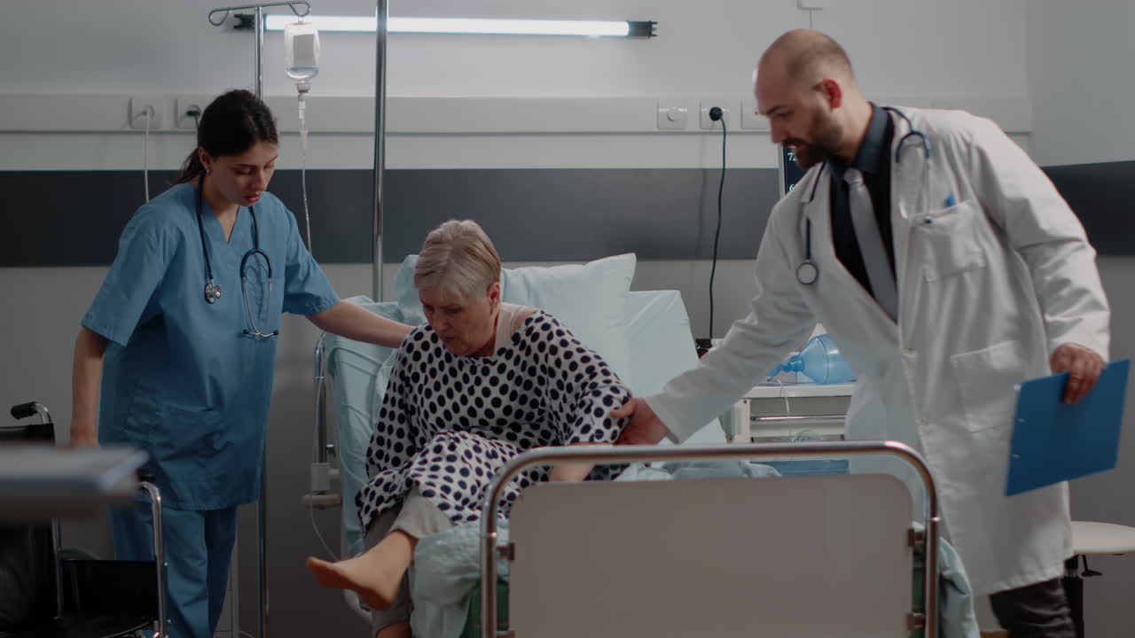 Doctor and nurse helping ill patient getting out of bed