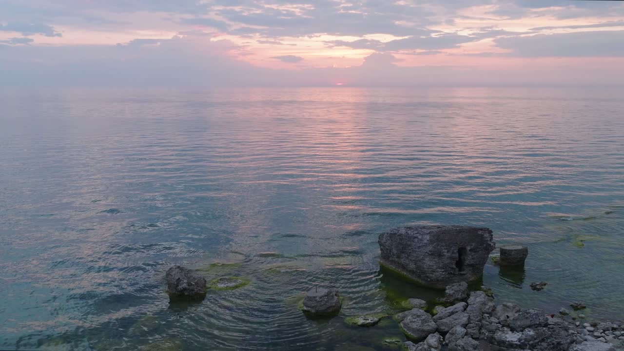 평온한 발트해 위의 활기찬 높은 대조적인 일몰의 아름다운 공중 전망, 지평선에 구름, 카로스타 전쟁 항구 콘크리트 해안 요새 폐허 리파자, 넓은 드론 돌리  ⁇  오른쪽으로 이동