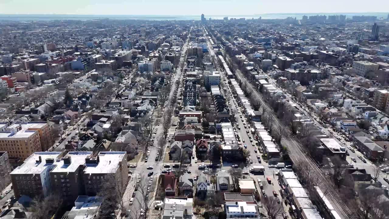 Horizontal drone fly-by shot over Avenue M in Brooklyn, capturing the city's vibrant streets, residential buildings, and dynamic urban landscape with smooth aerial movement.