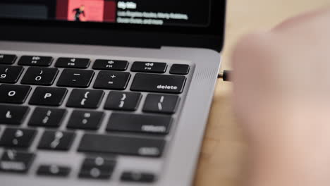 hand inserting headphones into macbook air for listening